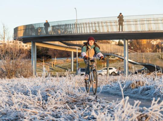 Manneskja á hjóli undir göngu- og hjólabrú á köldum degi í Reykjavík.