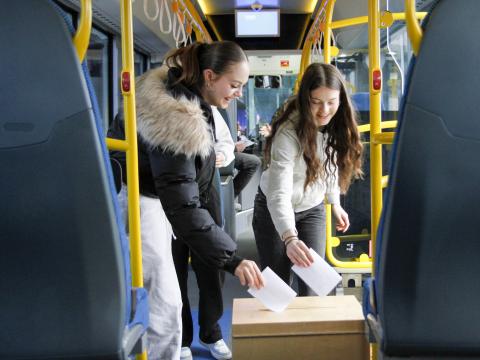 Tvær stúlkur í tíunda bekk setja atkvæði í kjörkassa í strætó. Uppákoman var hluti af dagskrá Lýðræðishátíðar unga fólksins