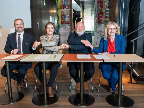 Fjórir einstaklingar haldast í hendur við skrifborð