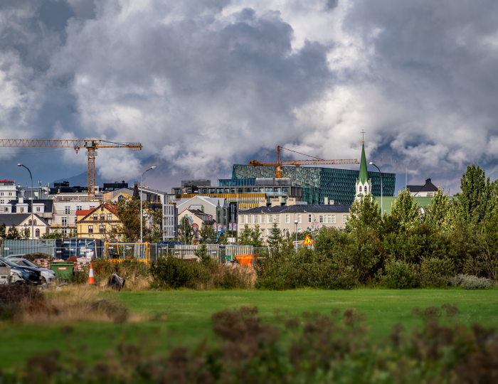 Byggingarkranar, grænt svæði og hús í Reykjavík.