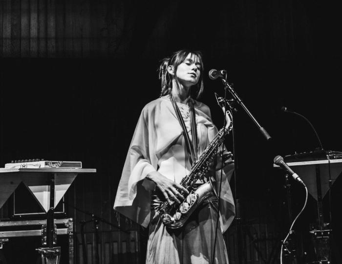 A woman plays saxophone on stage.