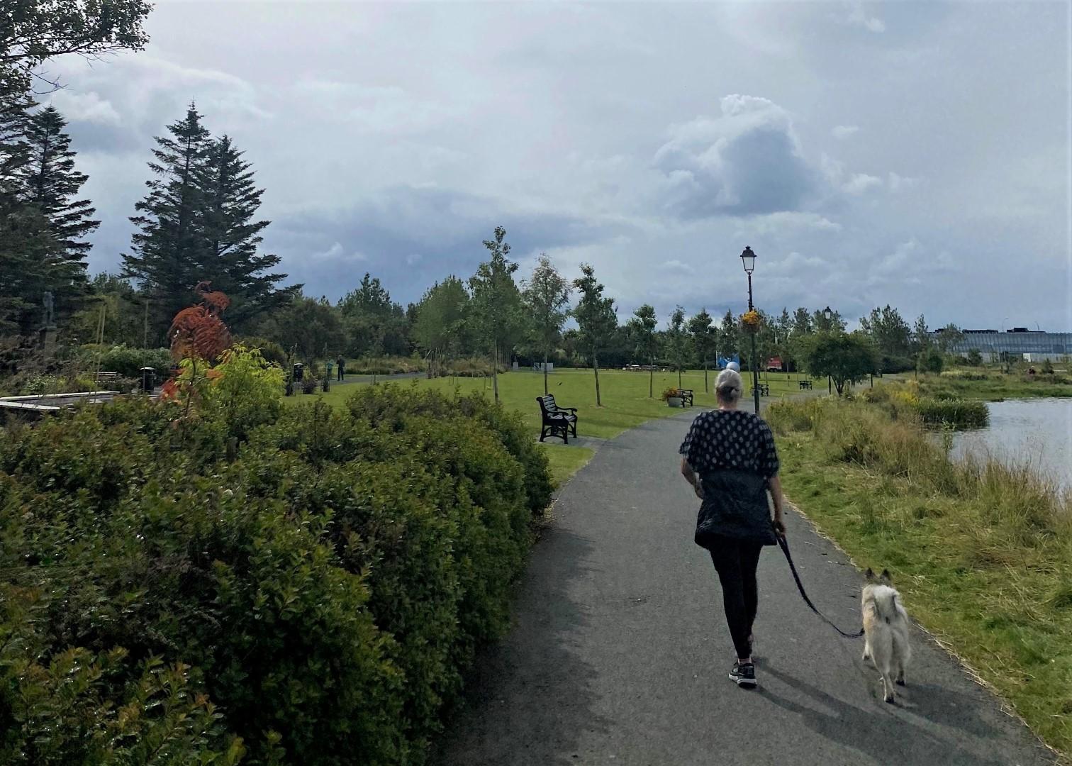Kona á gangi með hund í Hljómskálagarðinum