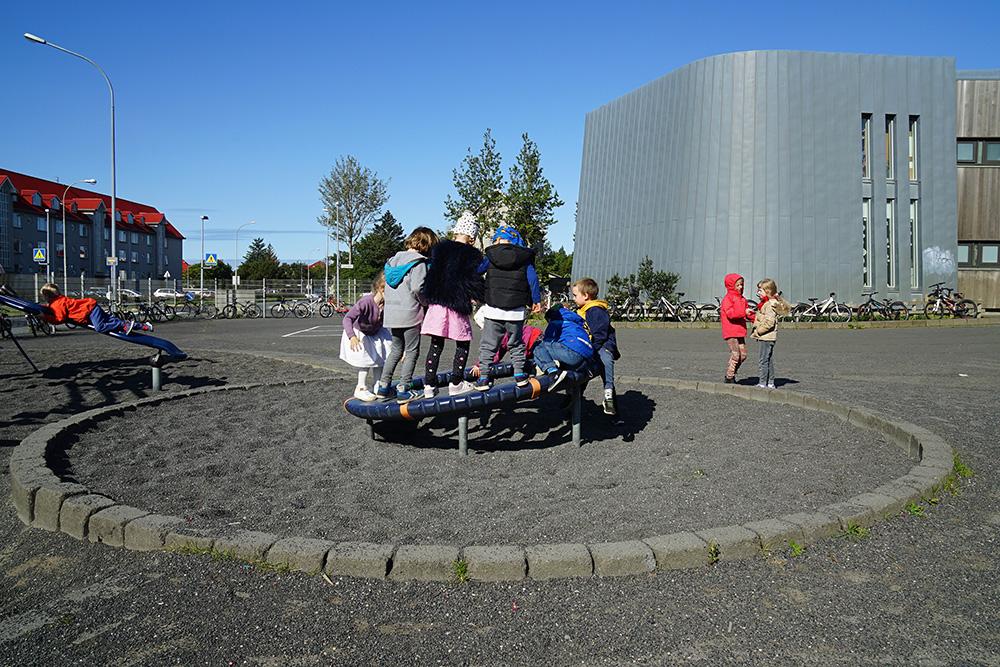 Children on playground equipment at Melaskóli grounds.