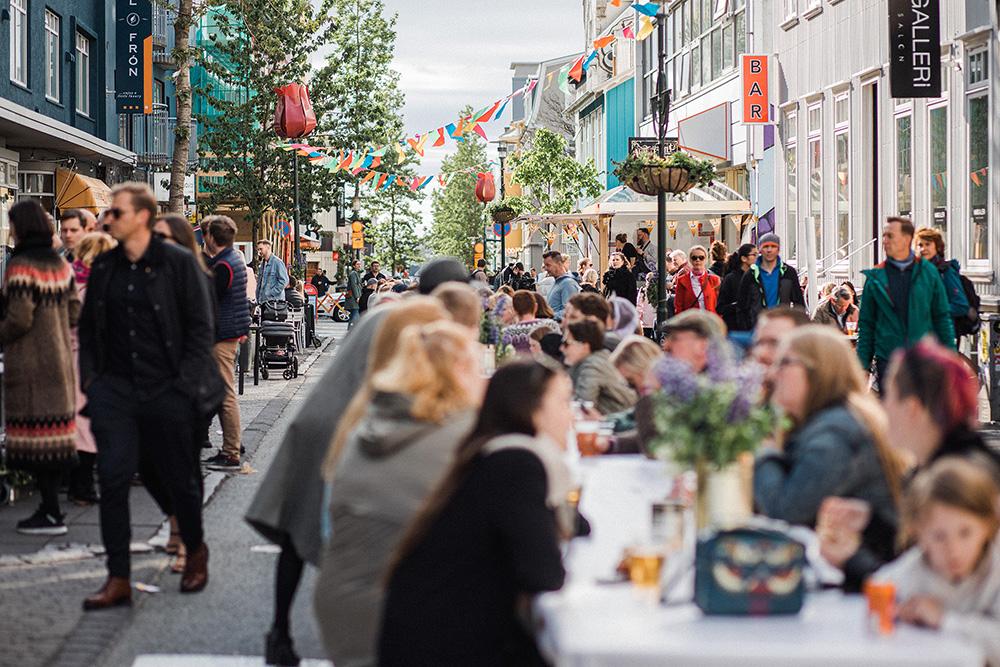 People dining at a long table on Laugavegur pedestrian street.