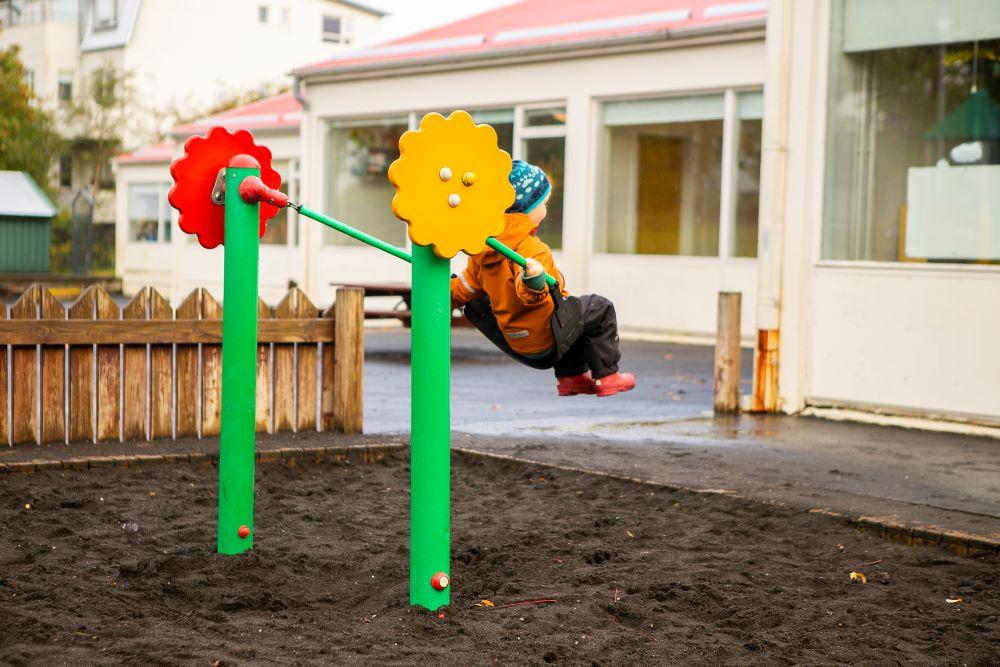 Barn að róla sér á útisvæði leikskólans Björtuhlíðar