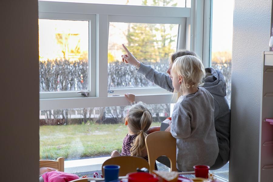 Children looking out the window with their preschool teacher