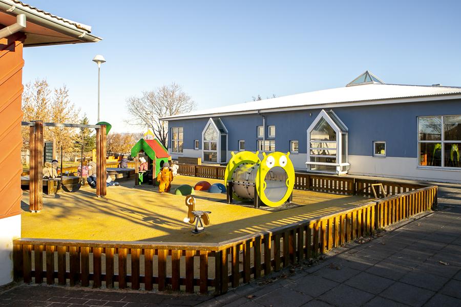 Children and playground equipment on Heiðarborg's grounds.