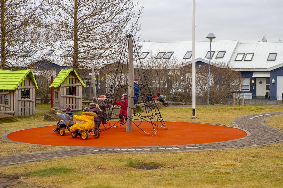 Börn að leik í klifurgrind og á þríhjólum á útileiksvæði Lyngheima.