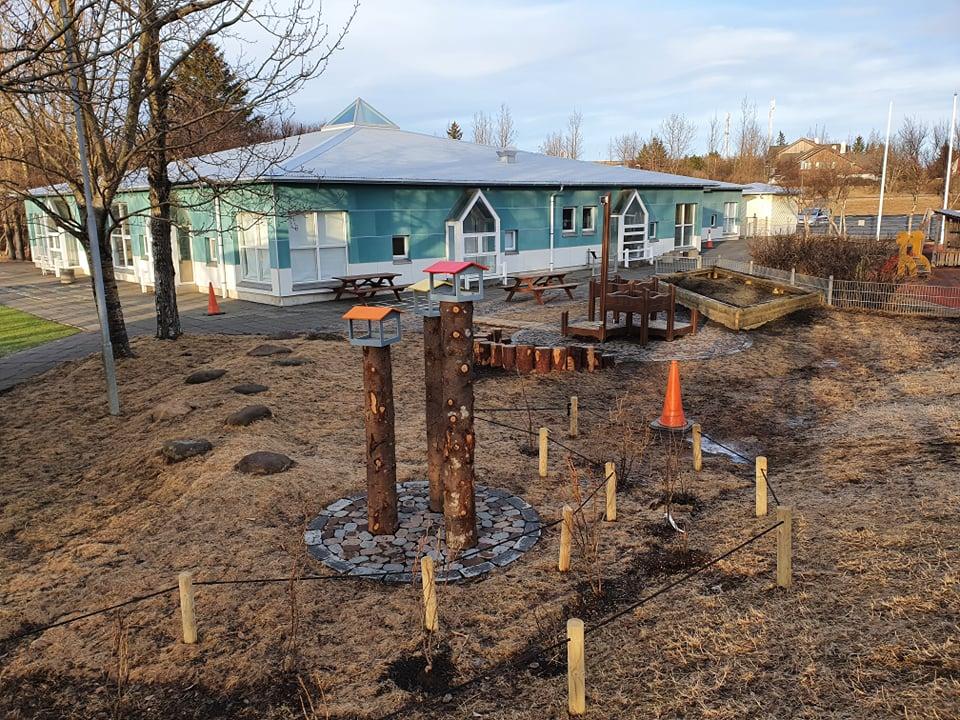 Leikskólinn Sólborg. Séð frá leiksvæði með fuglahúsum og leiktækjum
