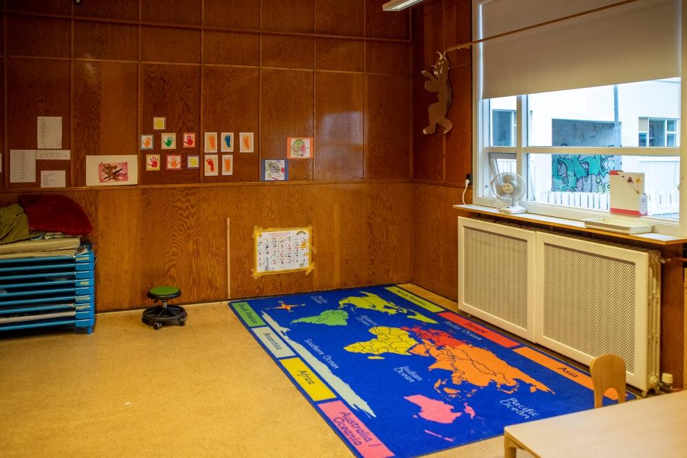 Panelveggur með listaverkum barna og litrík motta með heimskorti á leikskólanum Miðborg-Barónsstíg