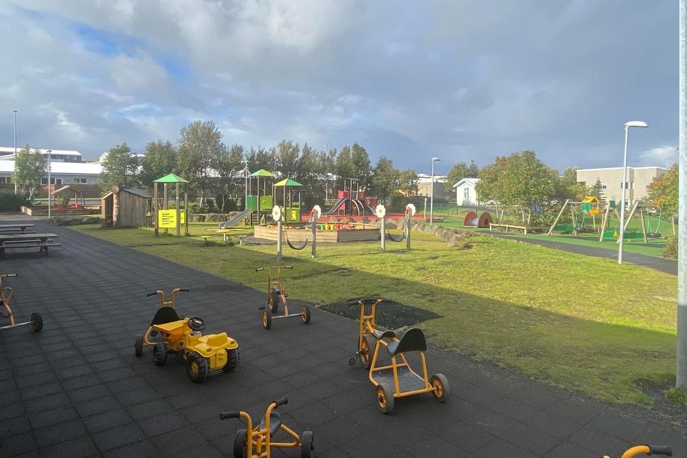 Yfirlitsmynd yfir útisvæði leikskólans Ness með þríhjól í forgrunni