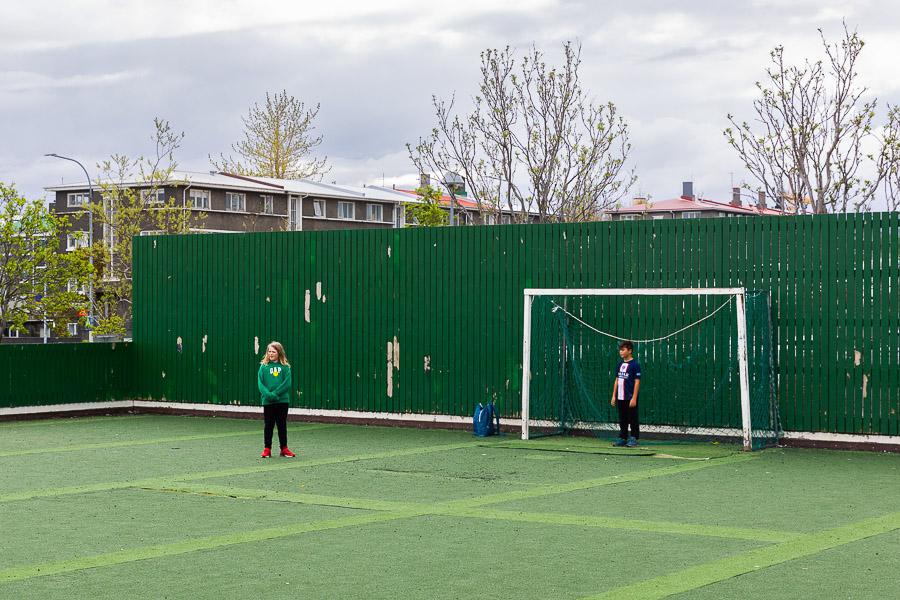Fótboltavöllur og börn að spila fótbolta. 