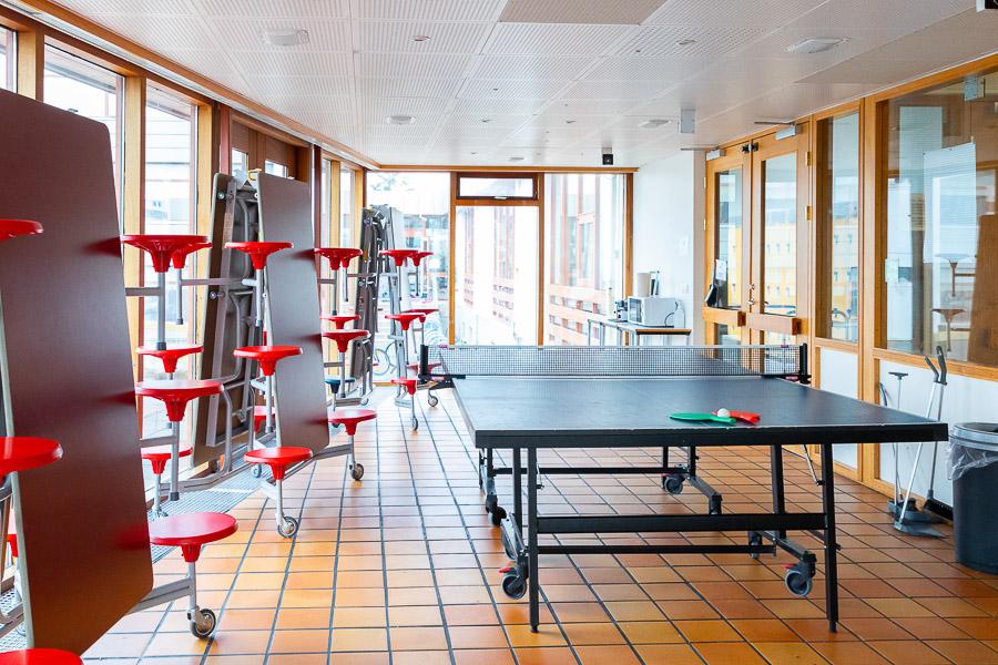 Herbergi með borðtennisborði og felliborðum til hliðar. 