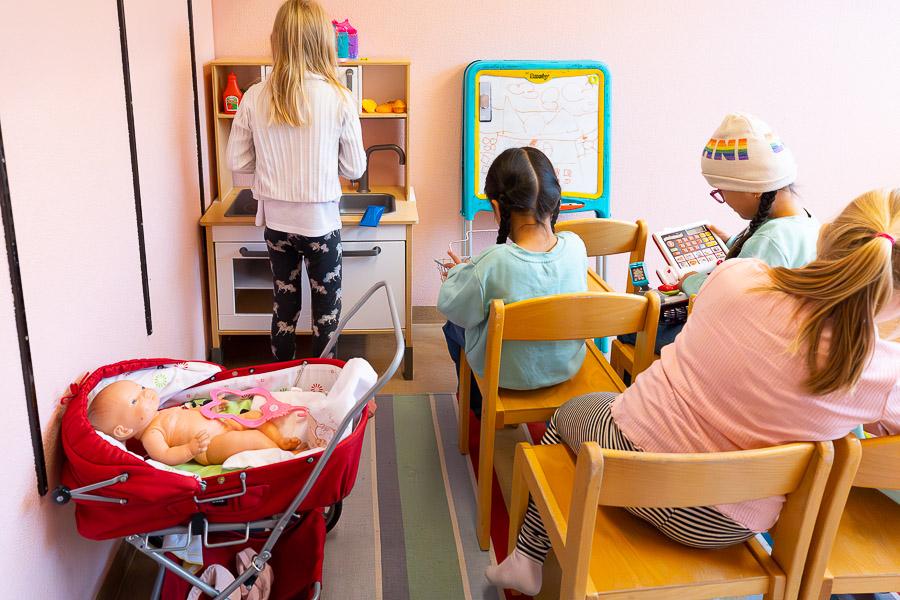 Children playing with dolls and at a toy kitchen.