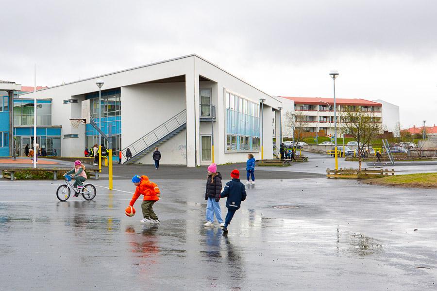 Children playing in the outdoor area of Hólabrekkuskóli. The school in the background. 
