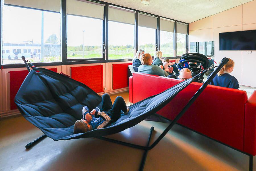 Hanging chair and children and staff sitting on a red sofa. 