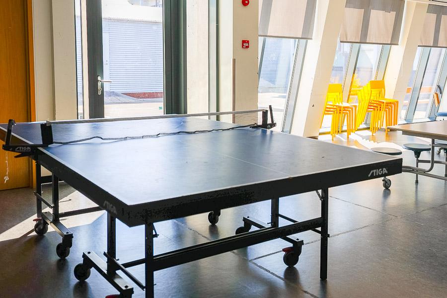 Salur með borðtennisborði, borðum og stólum. 