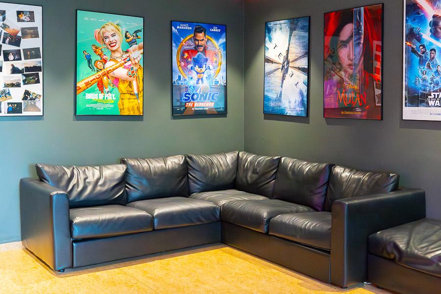 A black corner couch with a poster on the wall above it. 