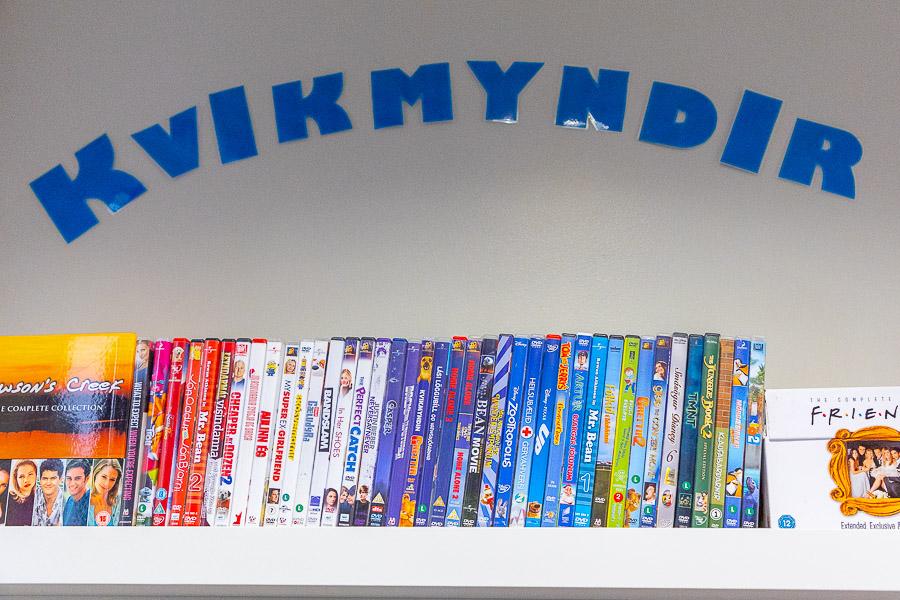 Shelf stocked with DVD movies. Above the shelf a sign reads "Movies" in Icelandic. 