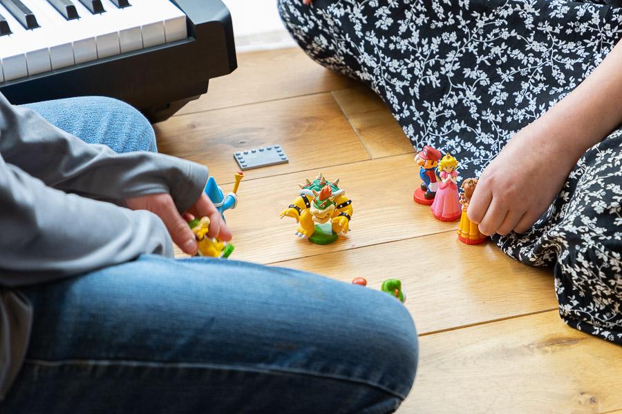 Children sit on the floor playing with small figurines.