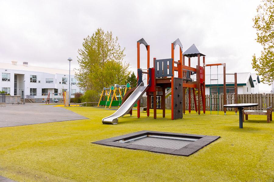Leikvöllur með kastala, rennibraut og trampolíni.