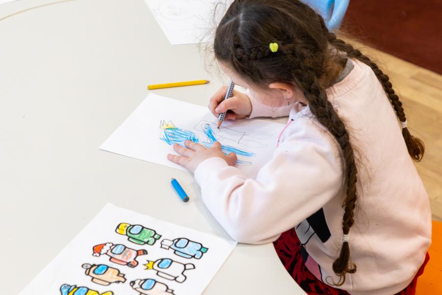 A child sits at a table drawing and coloring.