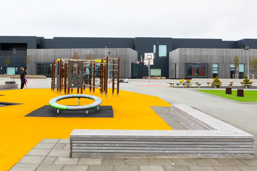 An outdoor play area with jungle gyms, benches, a basketball court and more. 