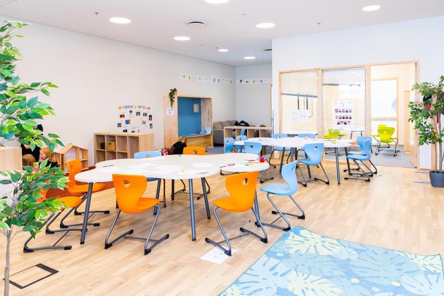 A hall with tables, chairs and a rug on the floor. 