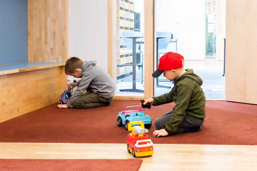 Children sit on the floor playing with cars. 