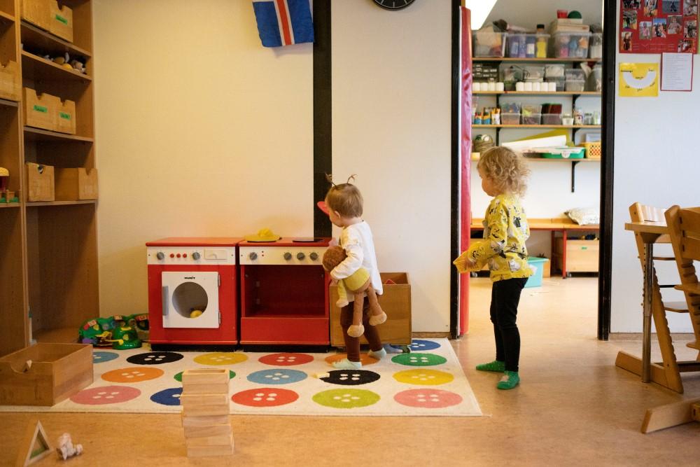 Börn að leika sé með leikfangaeldavél og þvottavél.