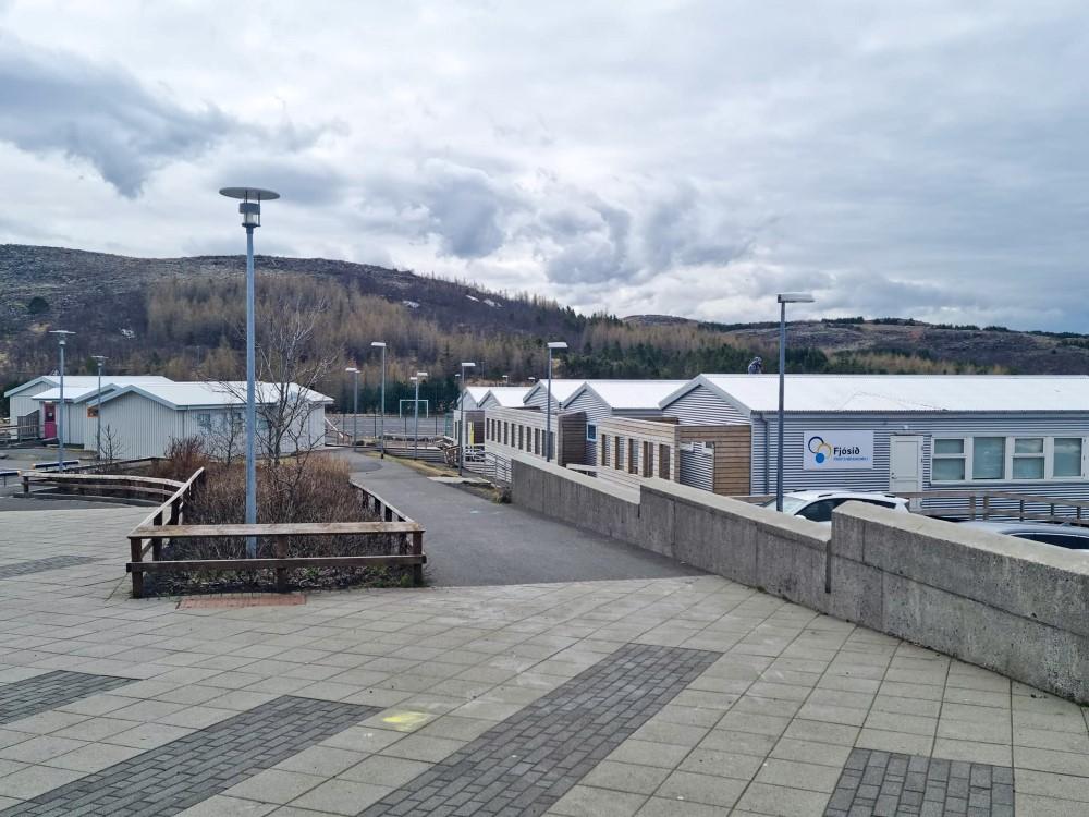 Hvít, lágreist hús sem standa í röðum. Stétt fremst á mynd og ljósastaurar.