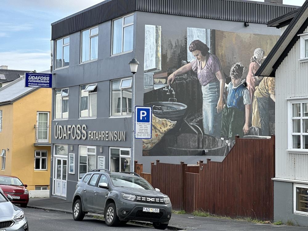 Bíll, hús og málverk á vegg.