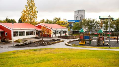 Leikskólinn Bjartahlíð séð frá grasbala á útisvæði
