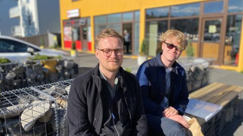 Tveir menn sitja á bekk fyrir utan Brauð & Co við Laugalæk.
