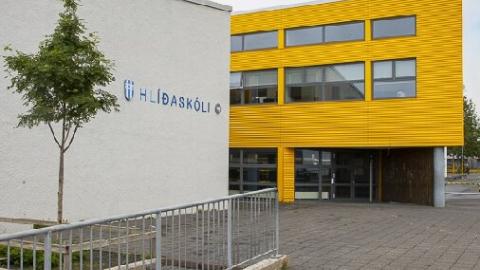 Photo of Hlíðaskóli. Two buildings, one white with the school's name written on the side along with the Reykjavík City logo, the other yellow.